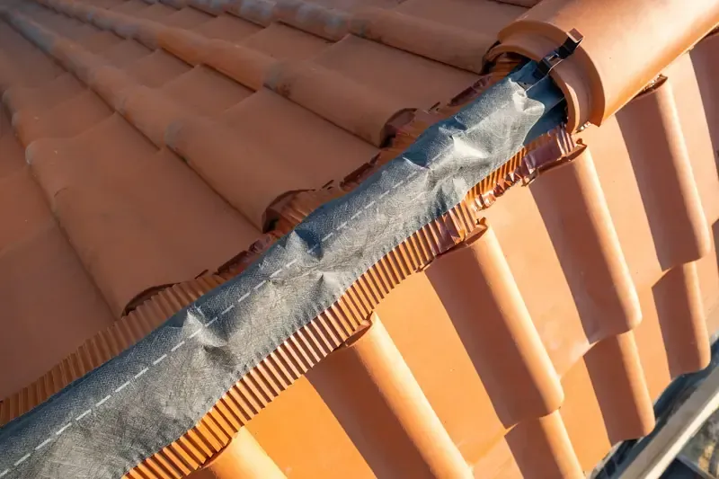 Pose d’un closoir ventilé sous les tuiles faîtières d’une toiture en terre cuite
