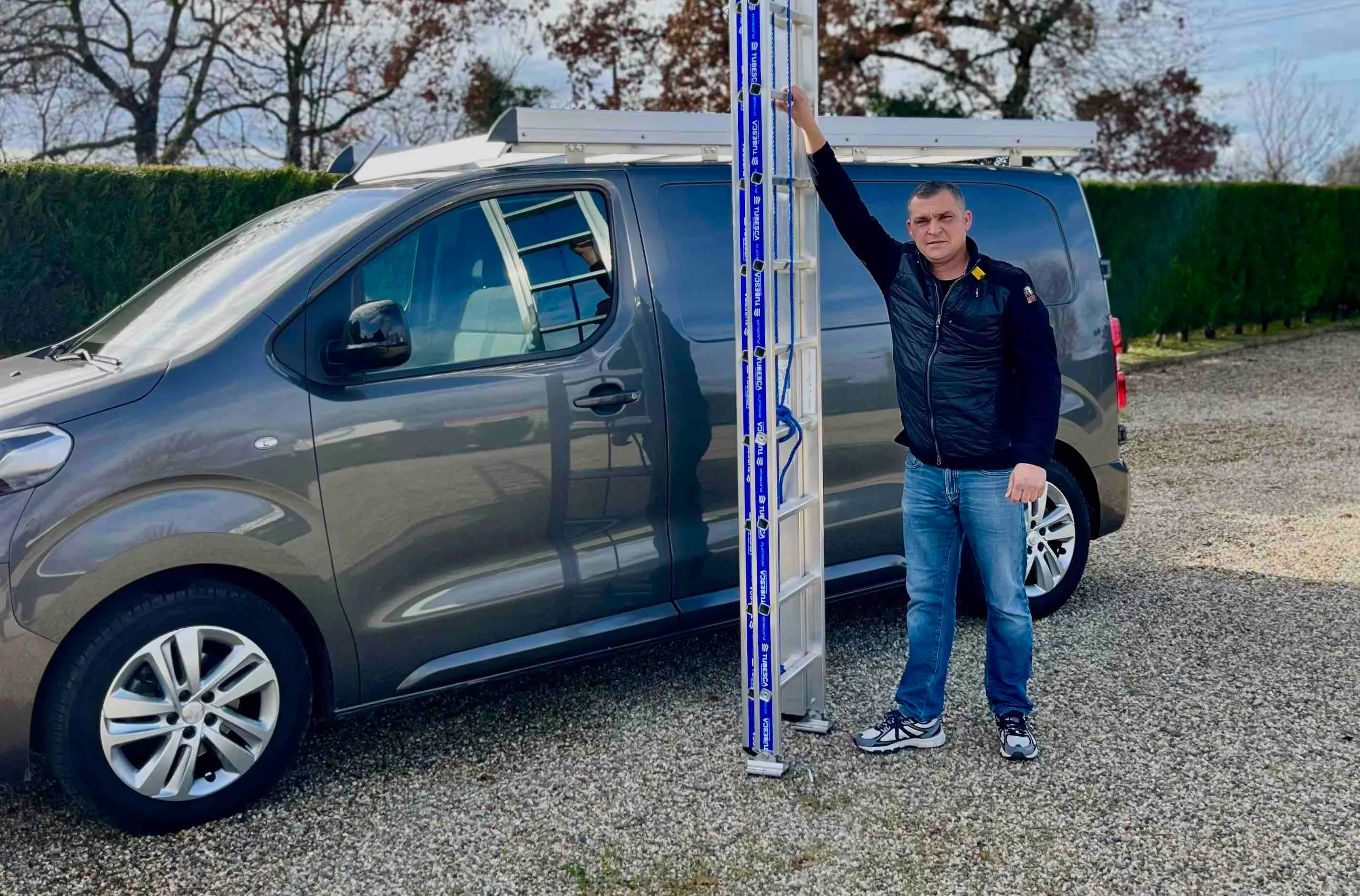 Tony Chasagrande avec une échelle devant son véhicule d’artisan