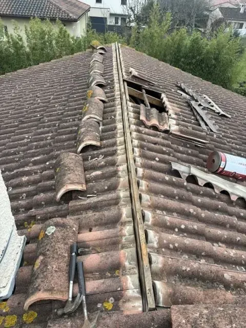 Toiture ancienne partiellement déposée avec tuiles de faîtage retirées et liteaux apparents