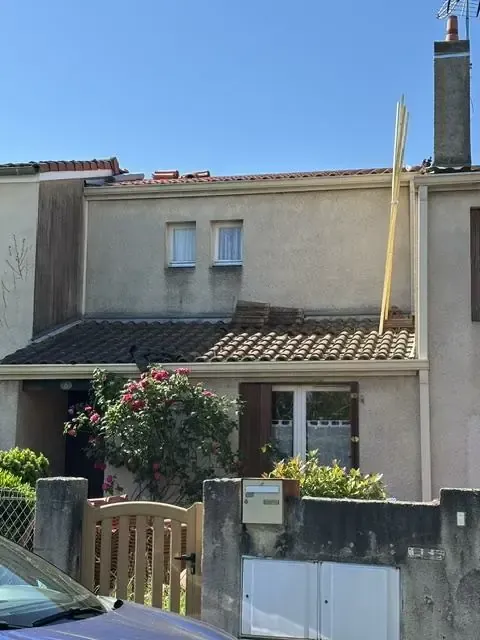 Toiture en cours de rénovation sur une maison mitoyenne avec liteaux dressés près de la cheminée