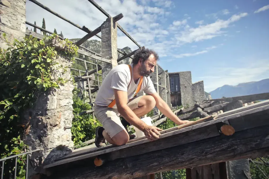 Artisan ajustant une pièce de bois sur une charpente ancienne en extérieur.